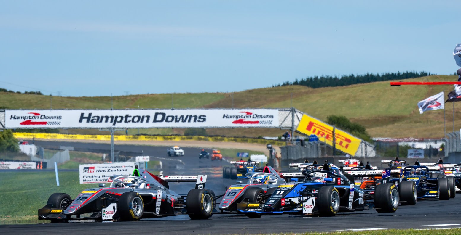 A race scene at Hampton Downs featuring several Formula 1-style race cars lined up on the track during a sunny day.